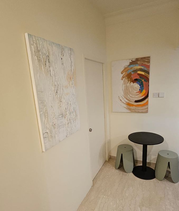 Dining corner with a round black table, two stools and abstract paintings