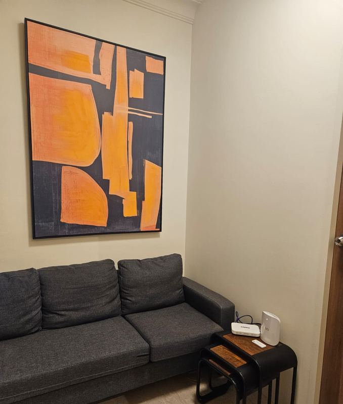 Living area with a grey three-seat sofa, nesting side tables and a large orange abstract painting